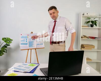 Online business presentation on the Internet. A man communicates with colleagues with a laptop. Stock Photo