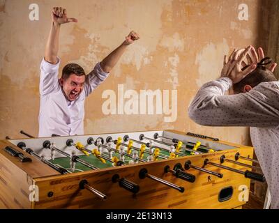 Colleagues are emotionally playing table football. Recreation and team building. Stock Photo