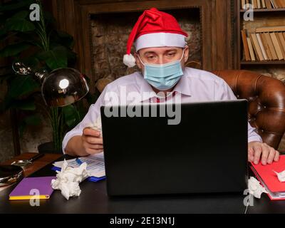 A sick worker in a Santa hat is talking on the Internet online. Stock Photo