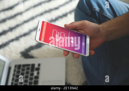 Man using audiobook application on modern smartphone at home, closeup Stock Photo