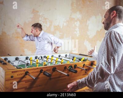 A man celebrates a victory in table football. Evening activities and relaxation. Stock Photo