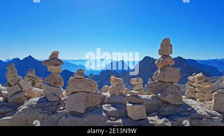 Several rock towers on front of landscape of mountain chain panorama of the European alps with sun and blue sky Stock Photo
