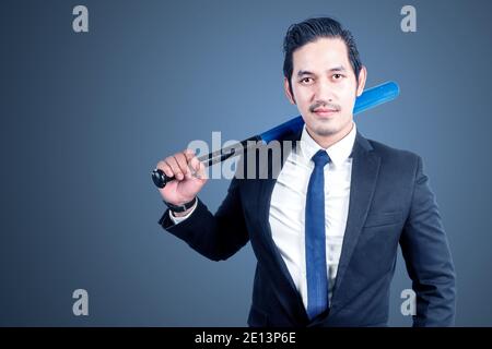 Asian businessman holding a baseball bat with a colored background Stock Photo