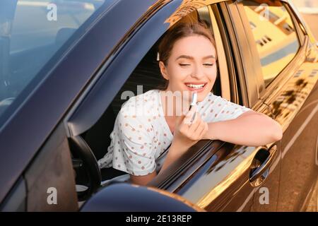 Beautiful woman applying lipstick in modern car Stock Photo