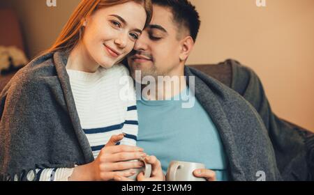 Charming ginger caucasian woman with red hair lying on the sofa with her boyfriend and having a tea together Stock Photo