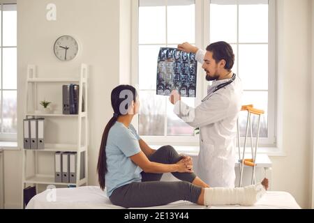 Trauma surgeon talking to woman and showing her X-ray image of her bone fracture Stock Photo