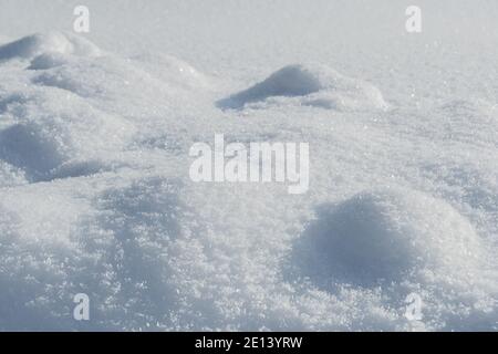 Smooth snow drifts on sunny winter day. Deep and high snow drifts illuminated by sunlight and being in shadow Stock Photo