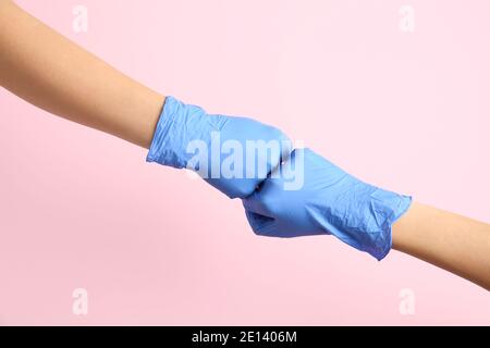 Hands in protective gloves bumping fists on color background Stock Photo