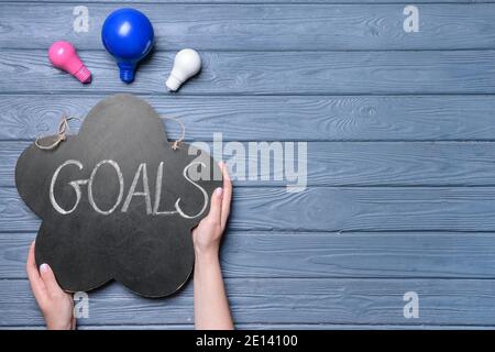 Female hands, light bulbs and word GOAL on wooden background Stock Photo