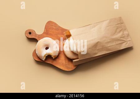Tasty donuts in paper bag on color background Stock Photo