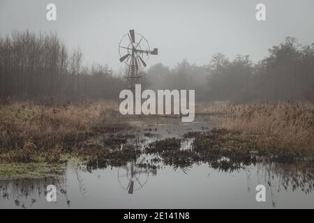 Old rusty metal windmill used to pump water away in a water landscape, photo taken during the winter in the nature reserve 'Lendenvallei' near the tow Stock Photo