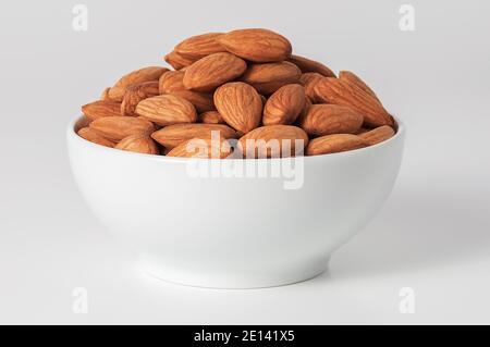 Almonds in a white Cup on a white background. Layout, mockup, place for logo and text. Stock Photo