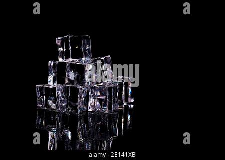 Ice cubes are arranged in a slide, isolated on a black background. Layout, mockup, place for logo and text. Stock Photo
