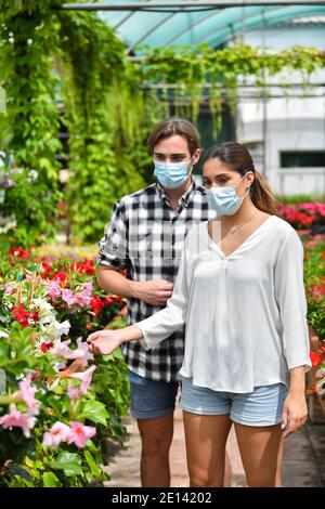 A couple wearing surgical mask checking some flowers at a beautiful garden center Stock Photo