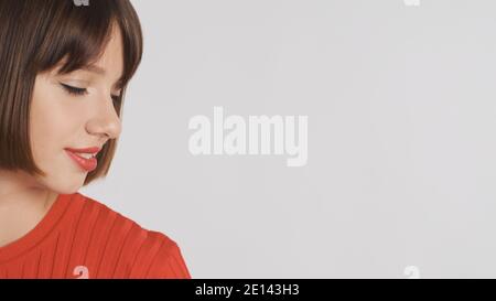 Close up beautiful brunette girl with bob hair and red lips looking at place for advertisement or promotional text isolated over white background. Cop Stock Photo