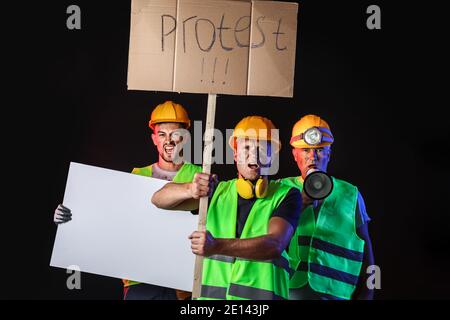 Protesting miner men with placards on dark background Stock Photo