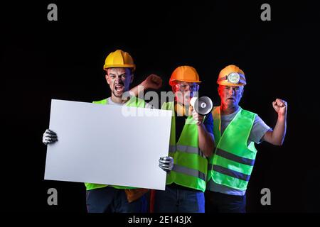 Protesting miner men with placard on dark background Stock Photo