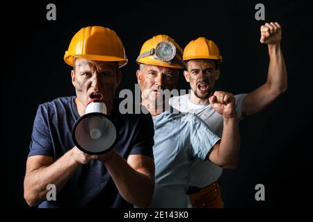 Protesting miner men with megaphone on dark background Stock Photo