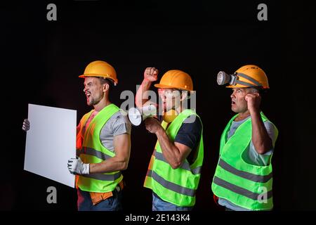 Protesting miner men with placard on dark background Stock Photo