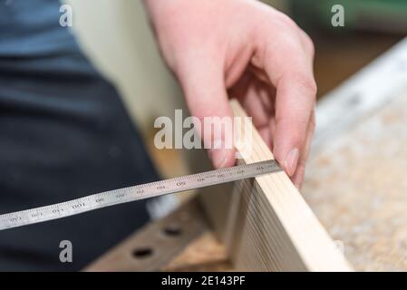 Carpenter Misses With Tape Measure Thickness Of Wooden Board - Closeup Stock Photo
