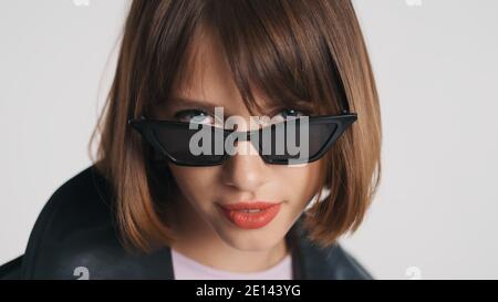 Portrait of beautiful blue eyed girl with bob hair and red lips wearing sunglasses isolated on white background Stock Photo