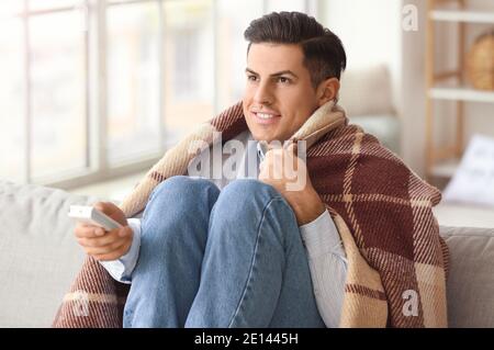 Man setting air conditioner to heat at home. Concept of heating season Stock Photo