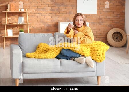 Woman setting air conditioner to heat at home. Concept of heating season Stock Photo