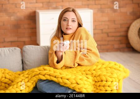 Woman setting air conditioner to heat at home. Concept of heating season Stock Photo