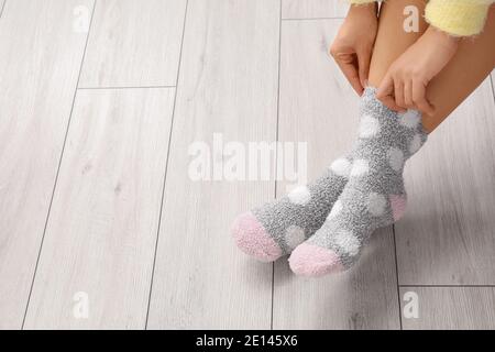 Young woman putting on socks at home Stock Photo