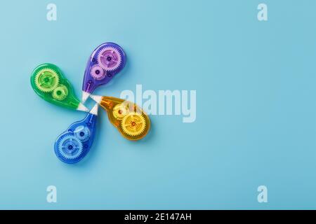 Stationery correction tapes are Multicolored on a blue background. Free space. The view from the top. Blue, green, yellow, lilac Stock Photo