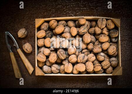 Walnuts In A Box Next To A Nutcracker On A Brown Wooden Table Stock Photo