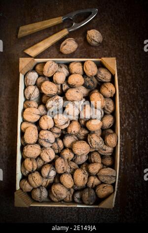 Walnuts In A Box Next To A Nutcracker On A Brown Wooden Table Stock Photo