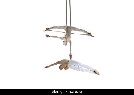 Forever young. Couple of acrobats, circus athletes isolated on white studio background. Training perfect balanced in flight, rhythmic gymnastics artists practicing with equipment. Grace in performance. Stock Photo