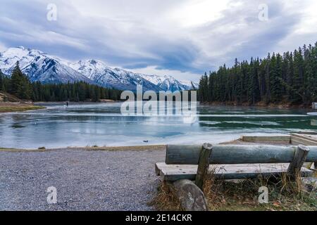 Johnson Lake frozen water surface in winter time. Snow-covered mountain in the background. Banff National Park, Canadian Rockies, Alberta, Canada. Stock Photo