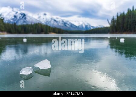 Johnson Lake frozen water surface in winter time. Snow-covered mountain in the background. Banff National Park, Canadian Rockies, Alberta, Canada. Stock Photo