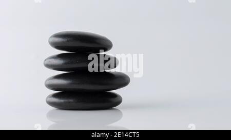 stacked black stones on white background Stock Photo
