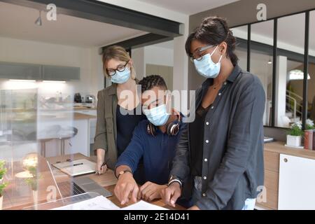 Coworkers in open space office, protected with plexiglas during 19-ncov pandemic Stock Photo