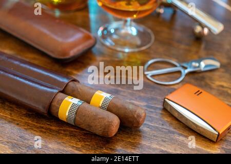Tobacco and alcohol. Cigar and brandy on a wooden table, closeup view. Cuban quality brand cigars and rum, smoking and drinking luxury lifestyle Stock Photo