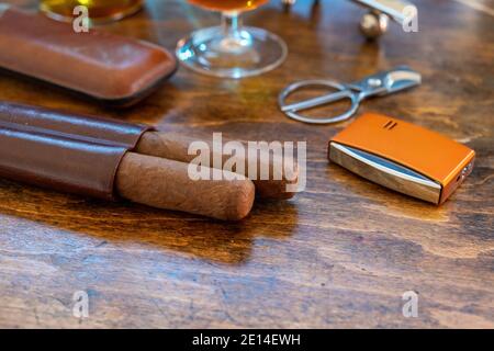Cigar and accessories on a wooden table, closeup view. Cuban quality cigars and brandy. Tobacco and alcohol, smoking and drinking luxury lifestyle Stock Photo