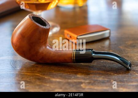 Tobacco pipe on a wooden table, closeup view. Handmade pipe from wood, smoking equipment Stock Photo