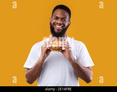 Cheerful African Man Posing With Burger Standing In Studio Stock Photo