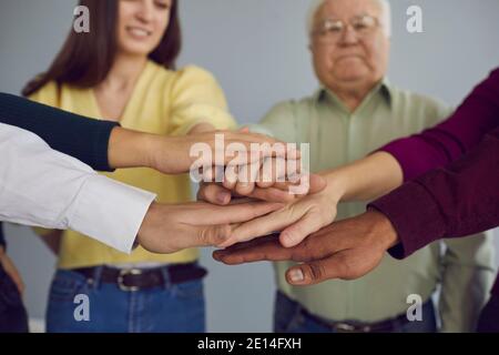 Group of multiracial young and senior people joining hands and supporting each other Stock Photo