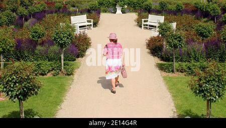 Eine fein gekleidete Dame mit Hut in einem Park. Stock Photo