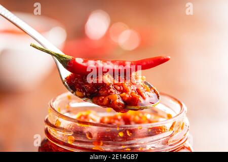 Red hot chili paste and chili pepper on spoon. Stock Photo