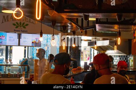 Mojo Market- Cape Town, South Africa - 16/12/2020 Artistically shaped neon light bulbs hanging over a kitchen in trendy restaurant in Mojo Market. Stock Photo
