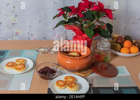 sweet cottage cheese pancakes in a plate and a clay pot, with jam on a server table Delicious cottage cheese dessert. High quality photo Stock Photo