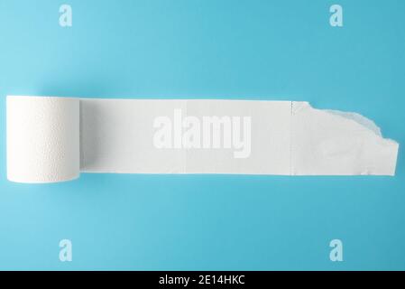 partially unrolled toilet paper roll isolated on blue background Stock Photo