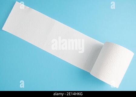 partially unrolled toilet paper roll isolated on blue background Stock Photo