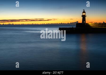 Sunrise and a lighthouse in Mevagissey harbour, Cornwall Stock Photo