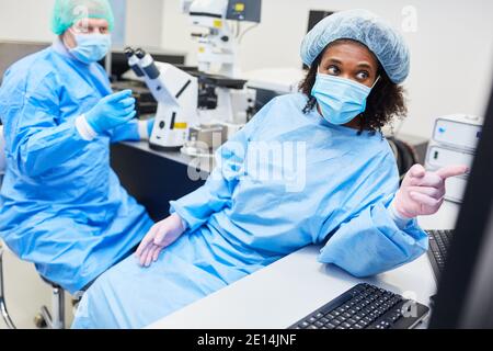 Researchers at breakthrough after evaluation on the computer in the laboratory looking for Covid-19 vaccine Stock Photo